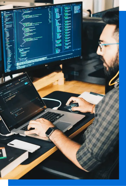 Image d'une personne qui code devant une fenêtre, entouré de végétation.