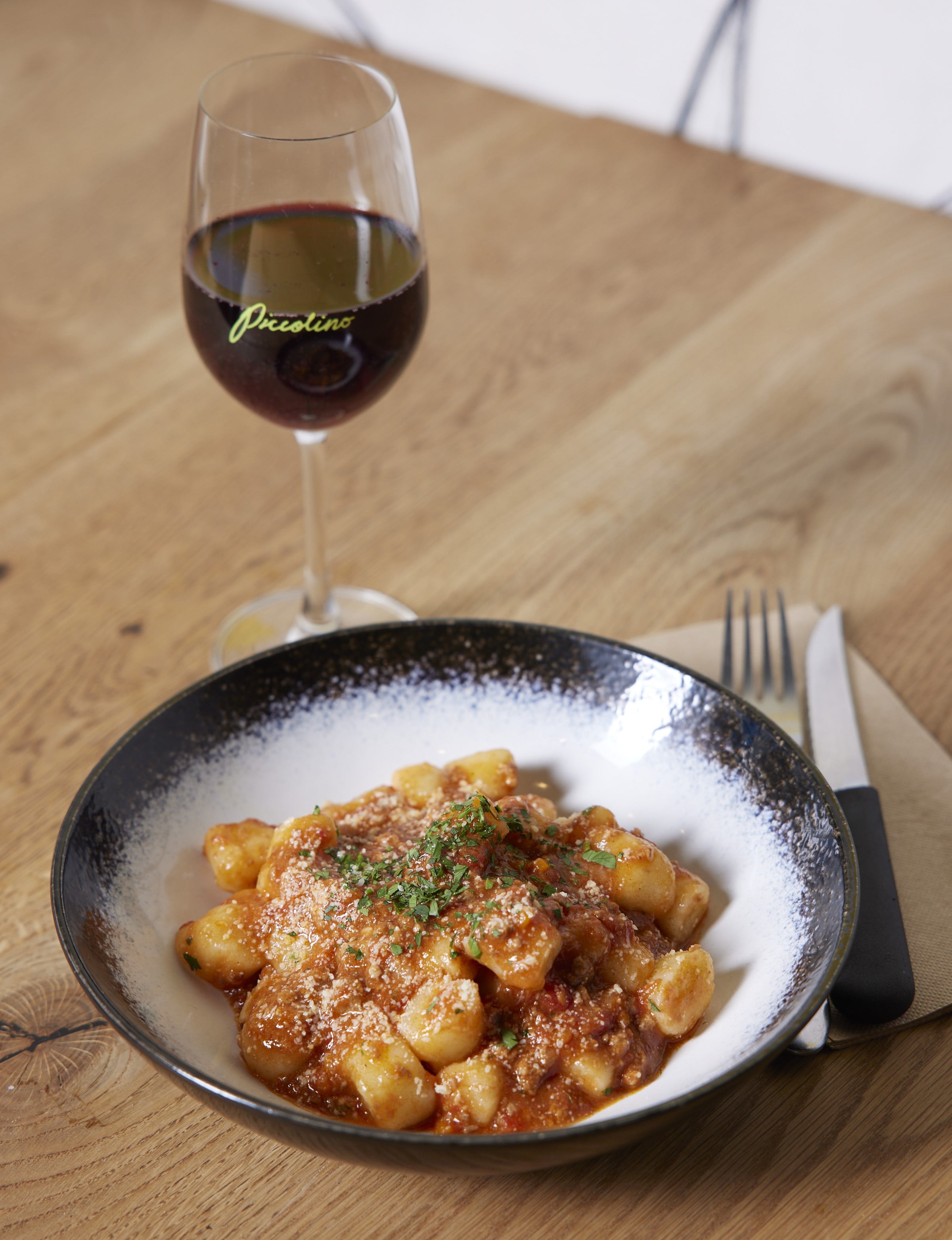 A bowl of house-made gnocchi with a glass of red wine at Piccolino