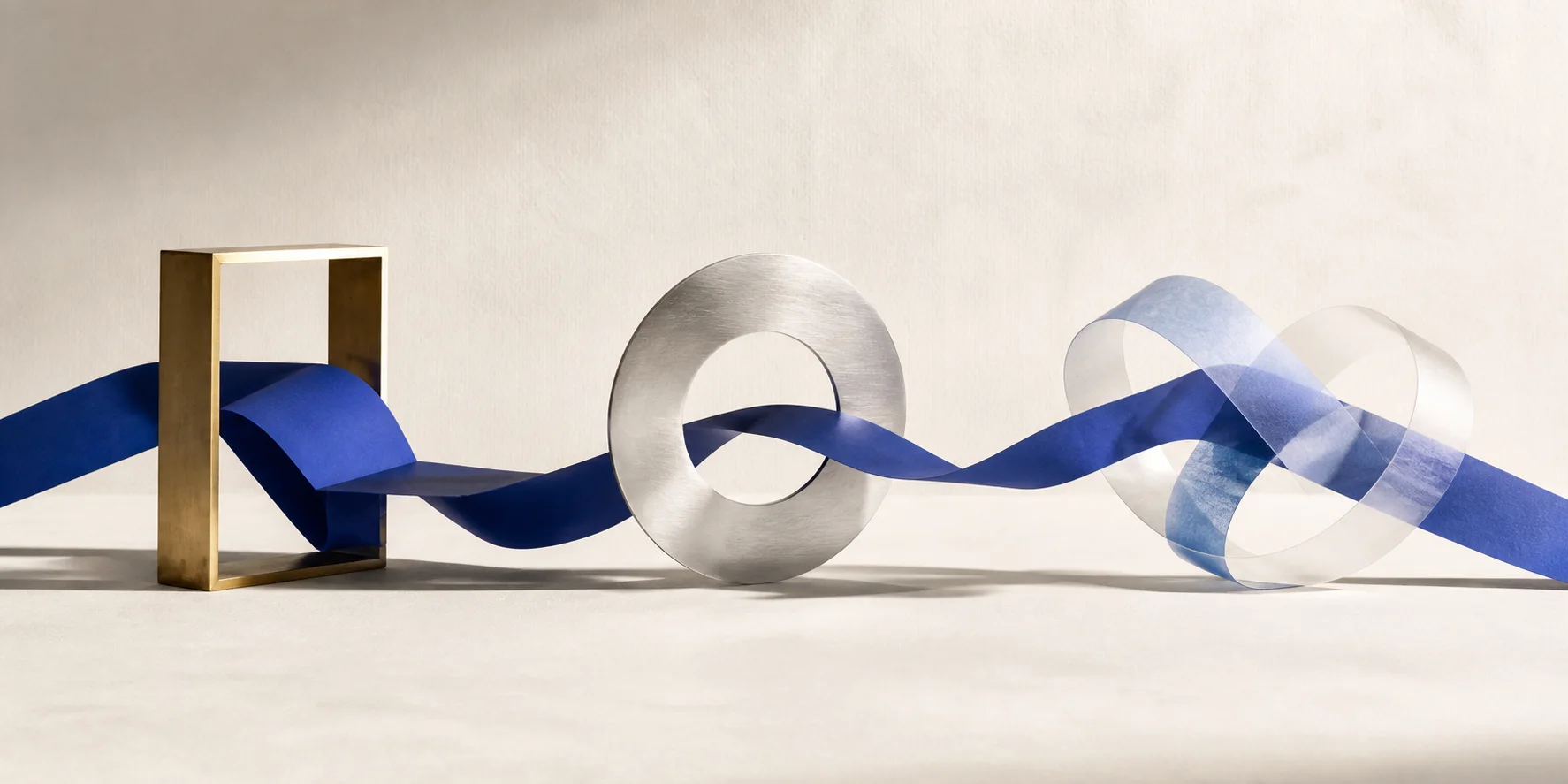 A cobalt ribbon moves through three handmade sculptural gestures