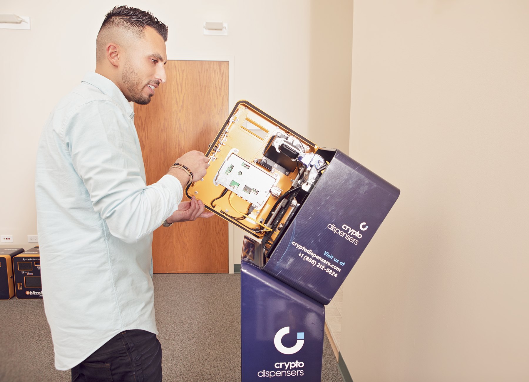 Firas Isa working beside an open Crypto Dispensers Bitcoin ATM in the office in April 2021.