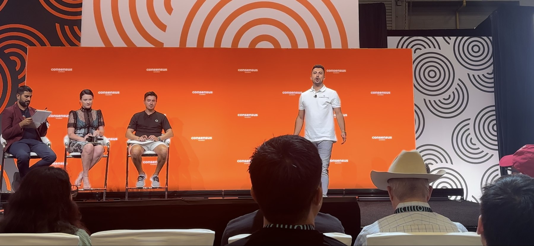 Firas Isa presenting Crypto Dispensers on stage at Consensus 2024 PitchFest before an audience and seated panelists.