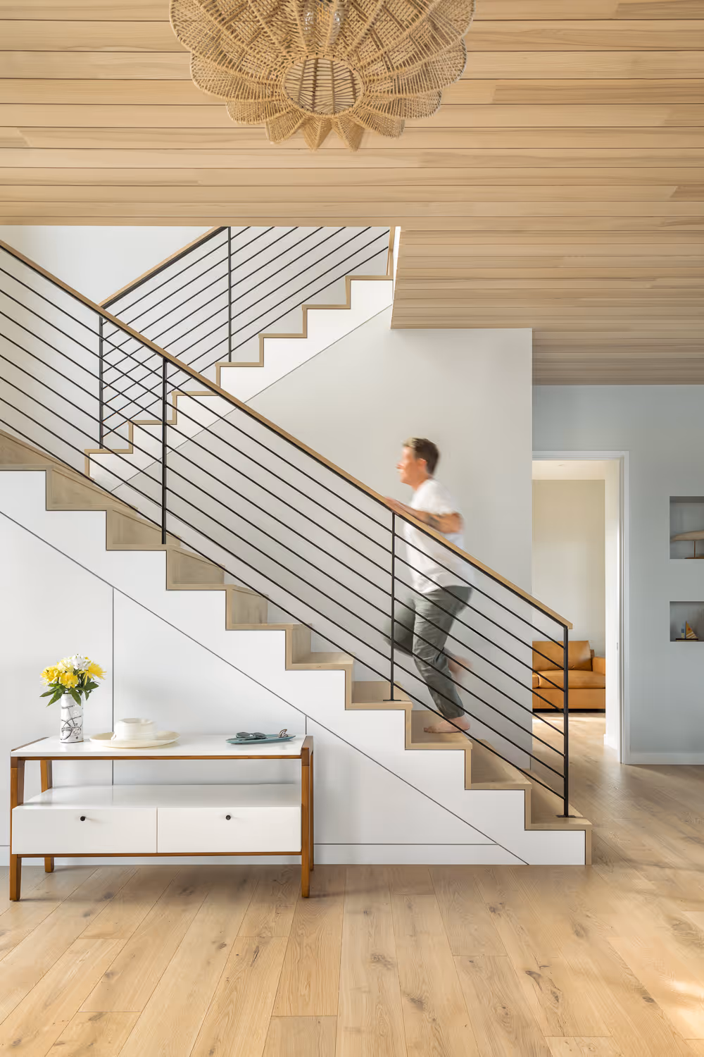 Modern staircase with metal railings, wooden floor, and woven pendant light