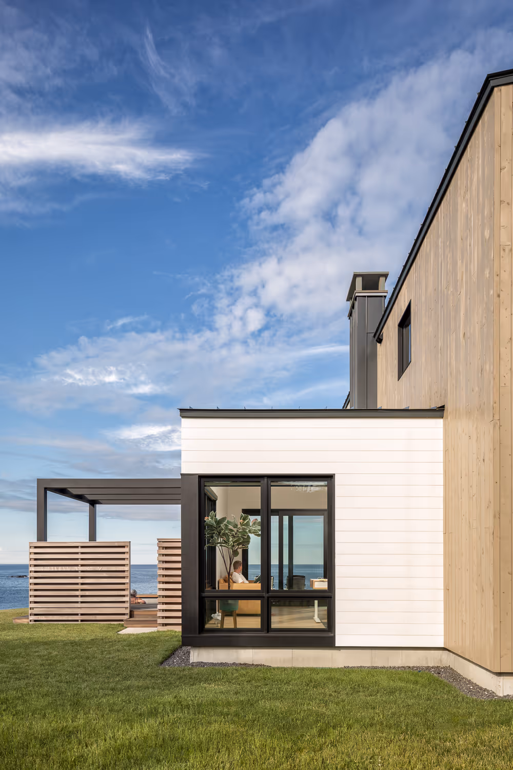 Modern beach house with large windows overlooking ocean and blue sky
