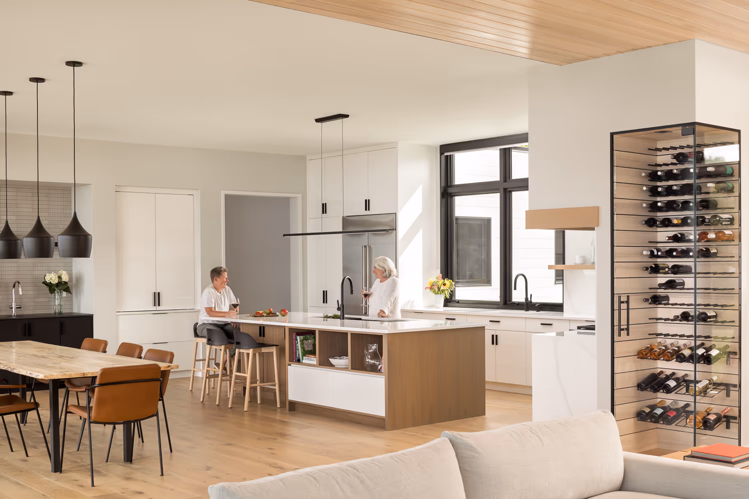 Modern kitchen with wine rack, island, and two people talking