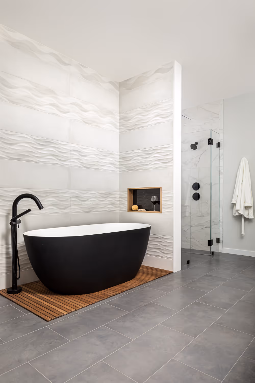 Modern bathroom with black bathtub, white textured walls, and glass shower