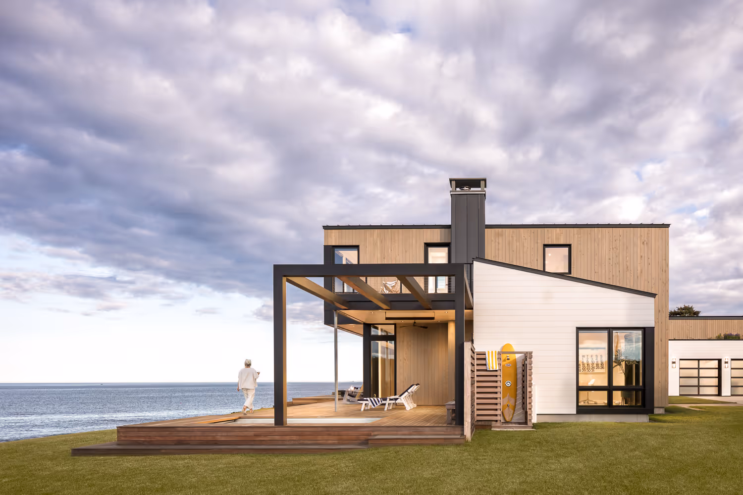 Modern beach house with wooden deck and ocean view under cloudy sky