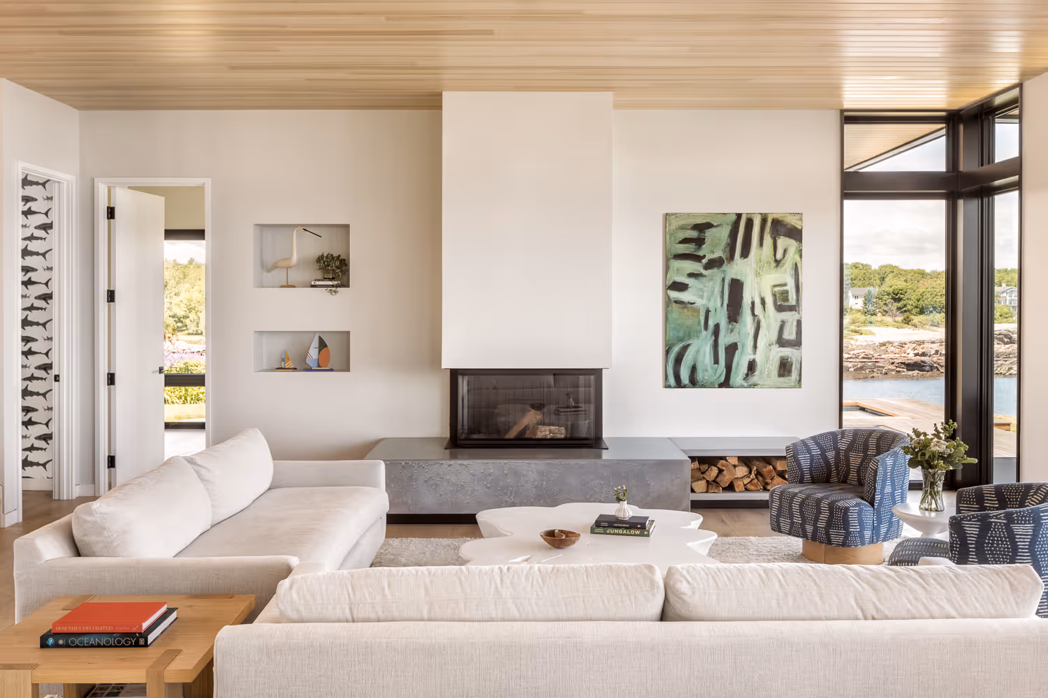 Modern living room with fireplace, ocean view, white sofas, and art