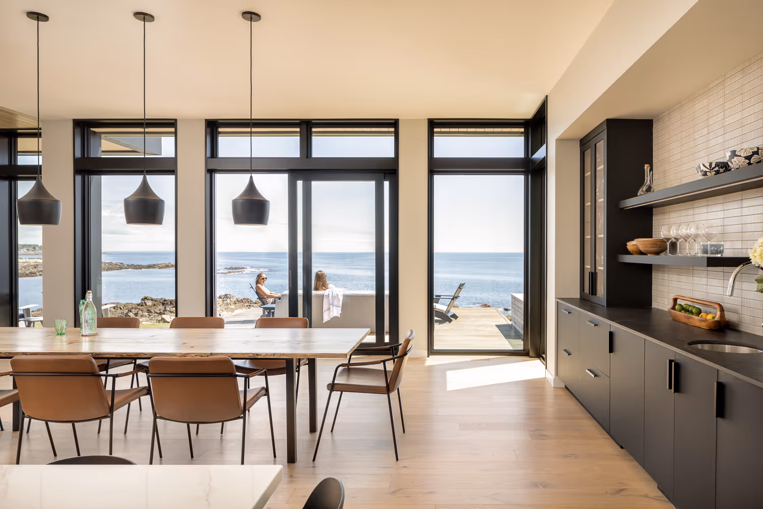 Modern kitchen with ocean view, pendant lights, and wooden dining table