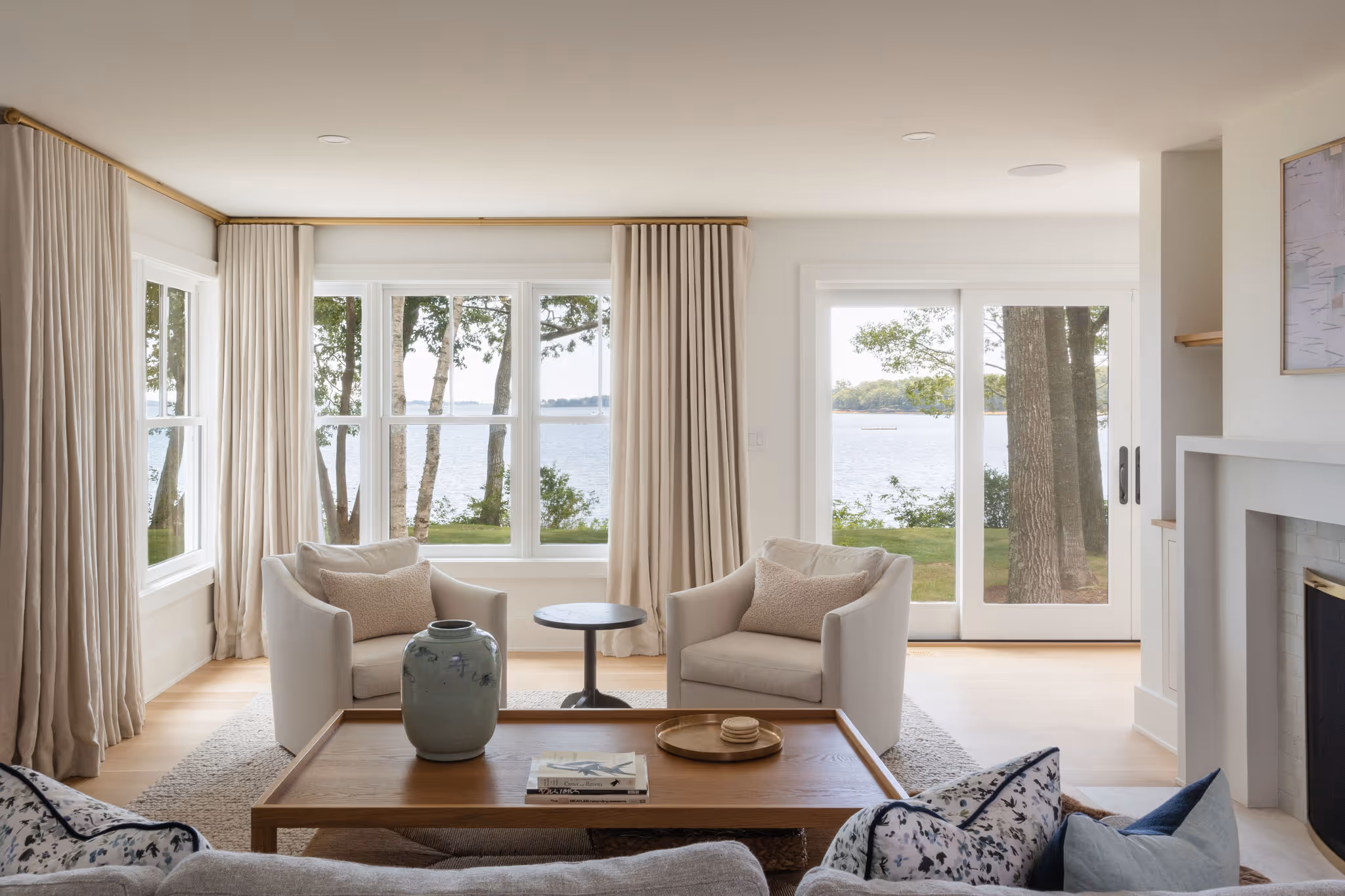 Bright living room with lake view, white chairs, and large windows