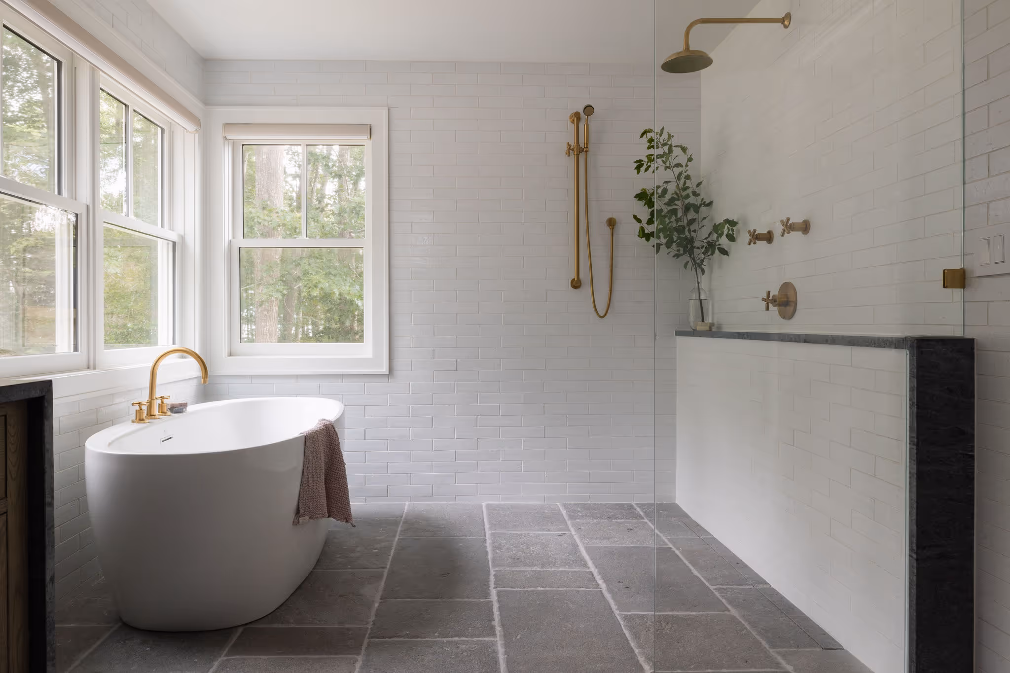 Modern bathroom with white tiles, freestanding tub, and gold fixtures