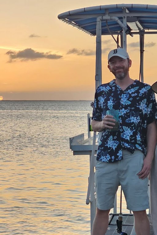 Person on the back of boat on body of water at sunset