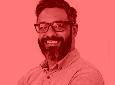 An image of a bearded man with glasses. The image is tinted red.