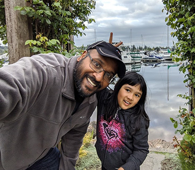 A photo of Bala and his child in front of some boats