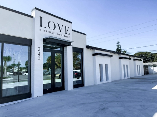 Modern white building with black-framed glass doors and windows, sign reads 'LOVE A Bridal Boutique' with street number 340.