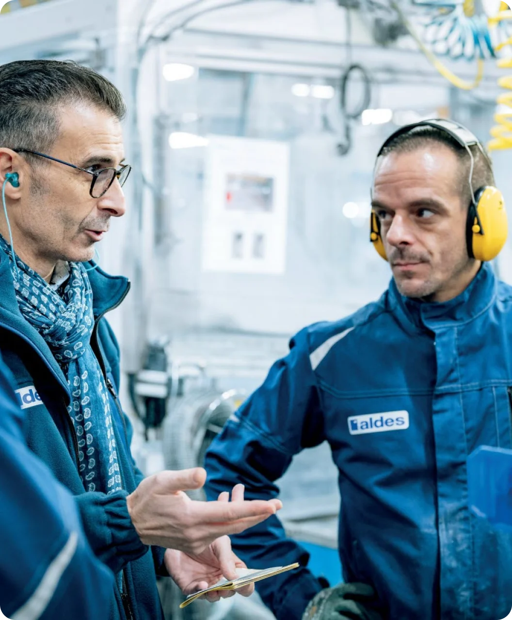 Two men standing close together, smiling at the camera.