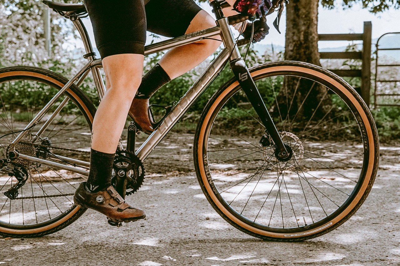 Close up of a rider pedaling a titanium Litespeed bike down a gravel road