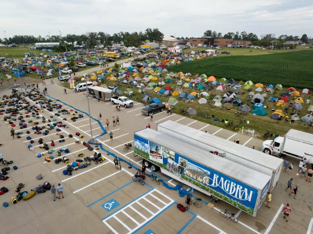 A RAGBRAI main campground filled with hundreds of colorful tents next to the luggage trucks