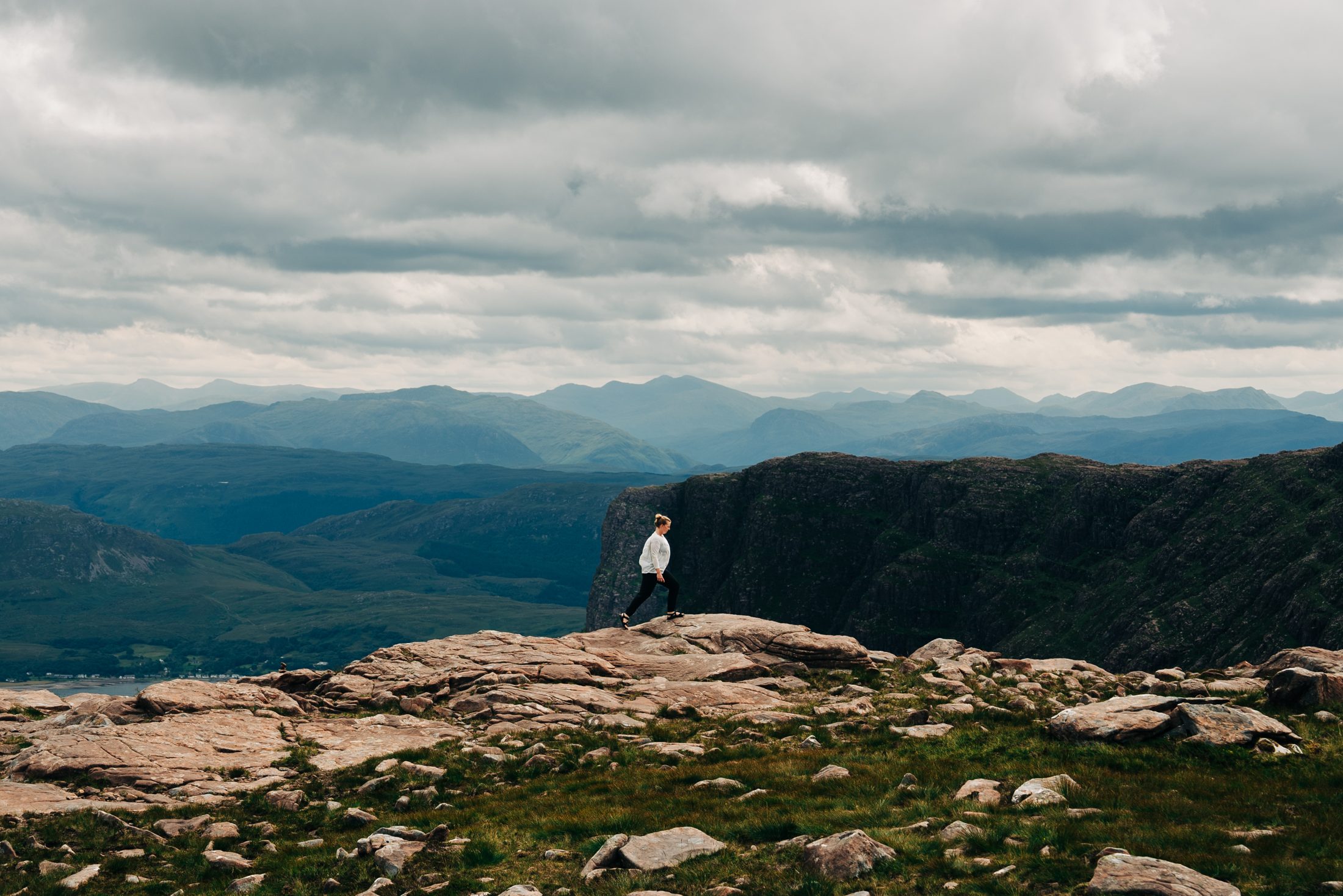 Standing on a cliff edge above the mountains on the NC500, Scotland