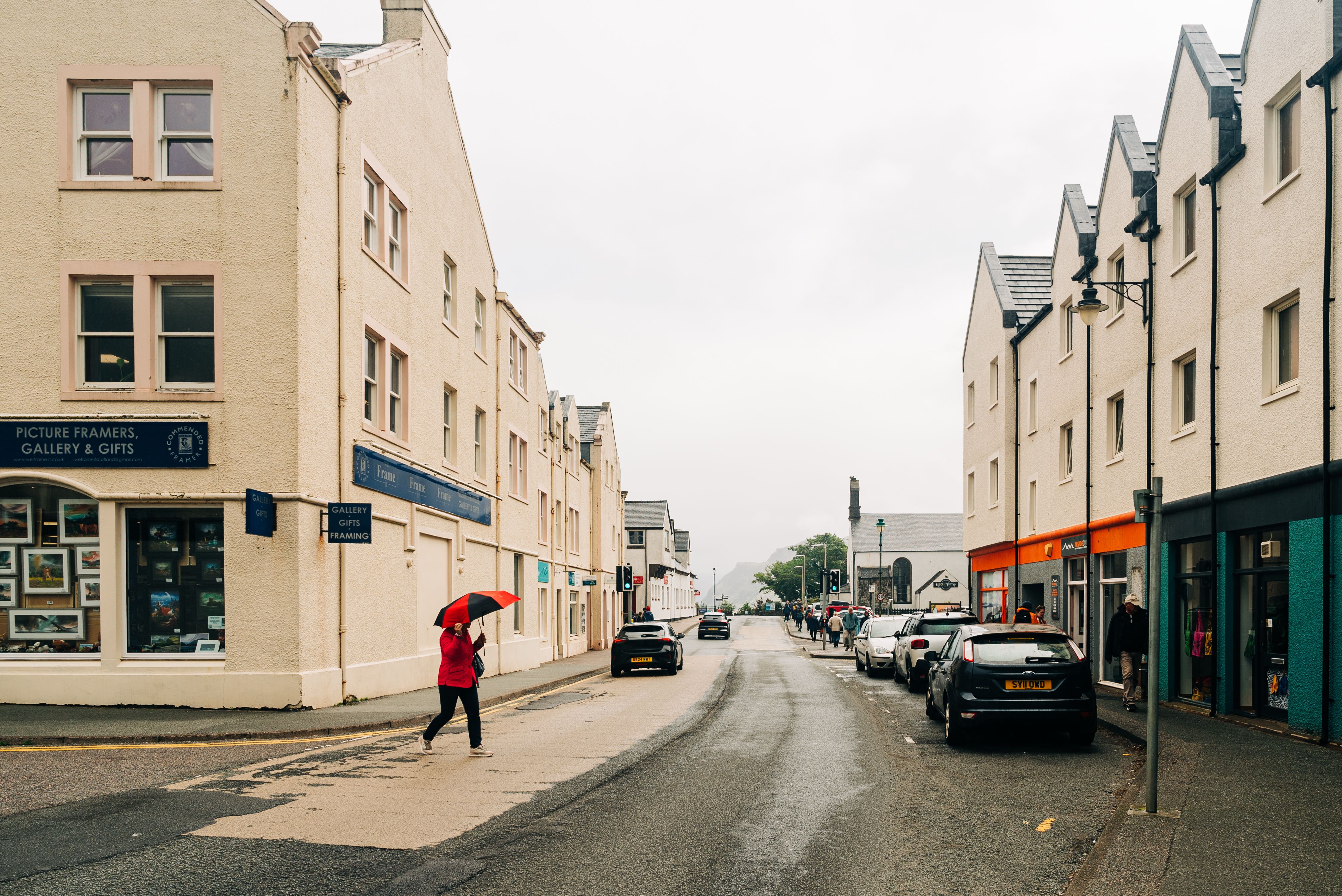 Person with umbrella crossing street in Portree, Isle of Skye, Scotland