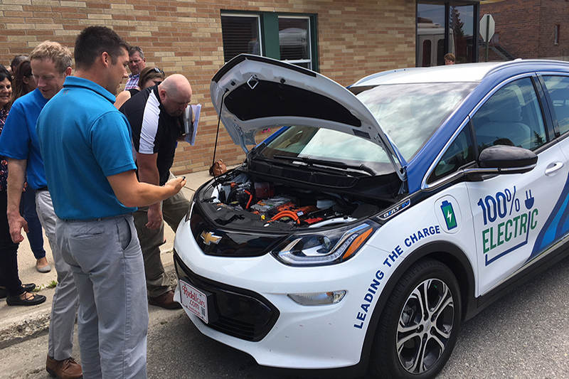People looking under the hood of the Bolt electric vehicle.