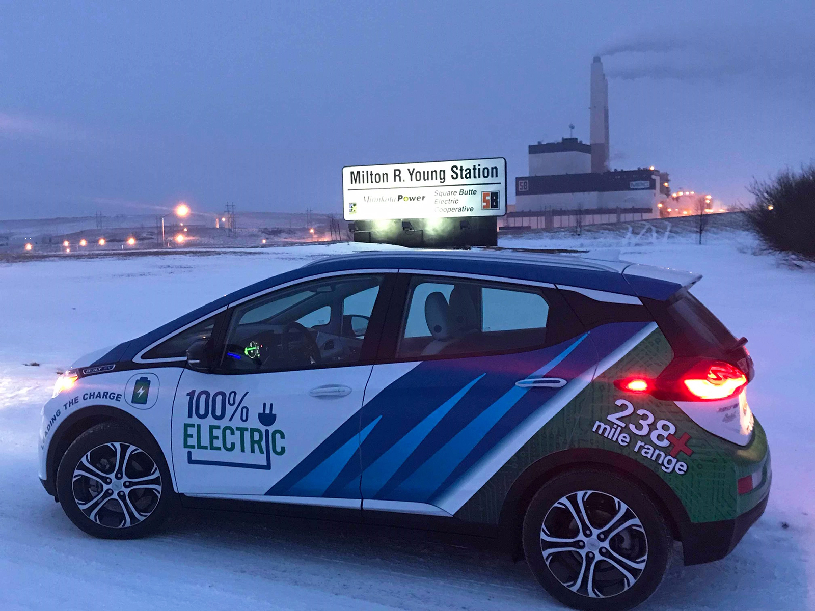 The Minnkota Bolt electric vehicle at night during the winter with the Milton R. Young Station in the background.