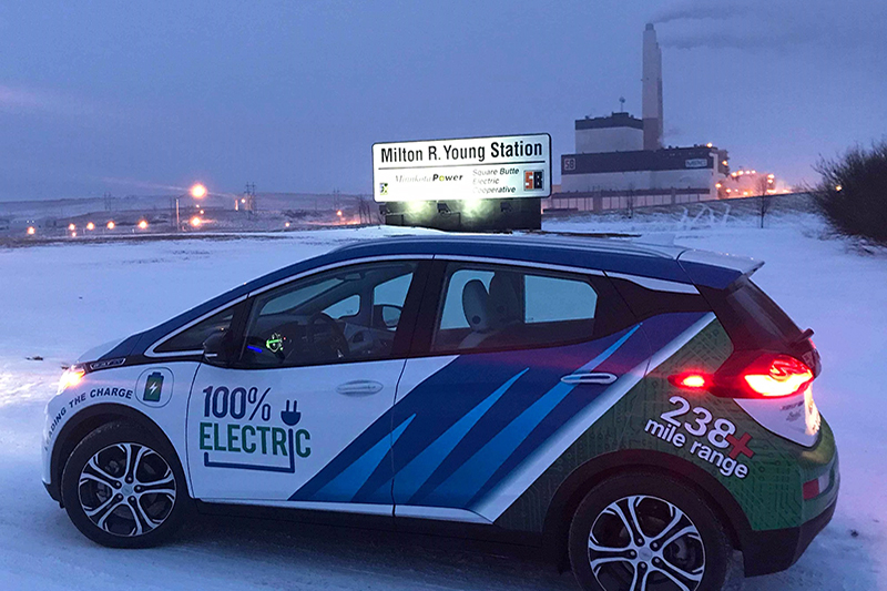 The Minnkota Bolt electric vehicle at night during the winter with the Milton R. Young Station in the background.