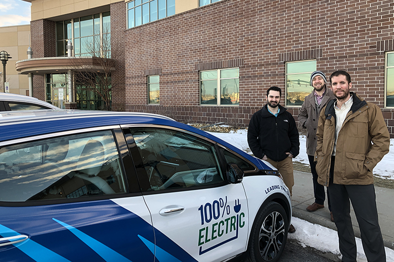 Minnkota Power Delivery employees stand outside by the Bolt electric vehicle.