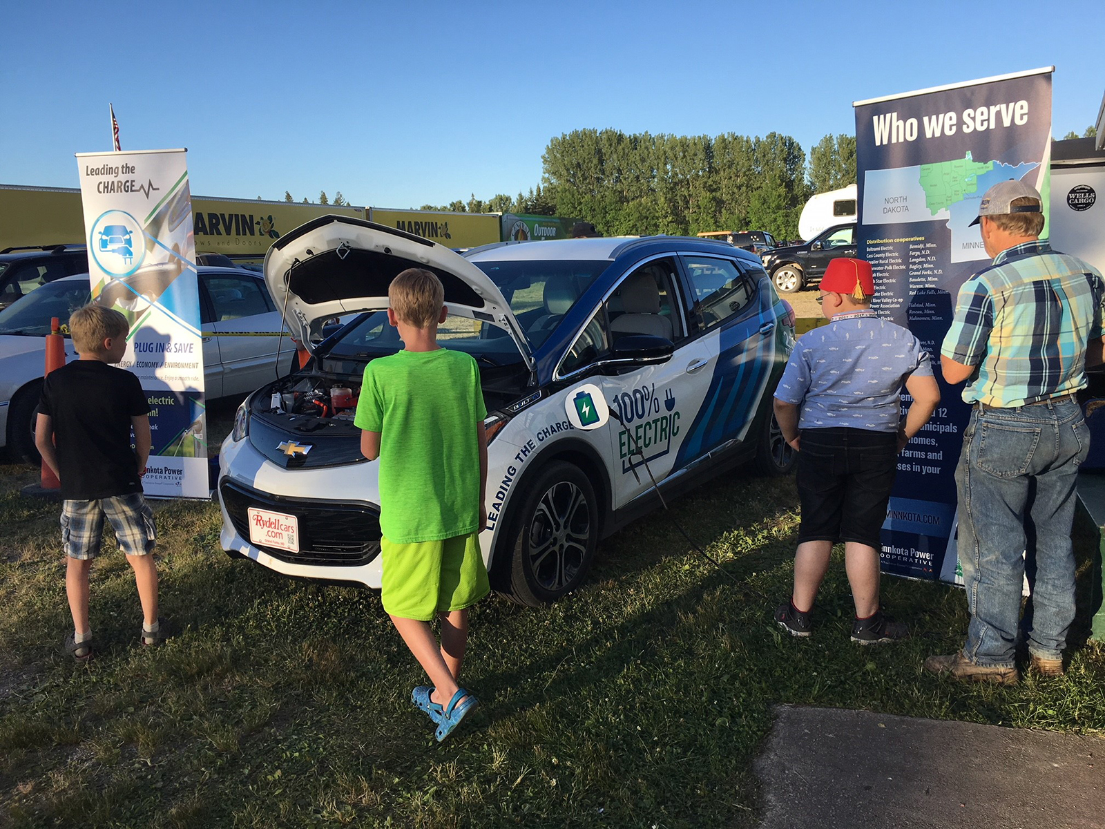 A few people looking at Minnkota's Bolt electric vehicle on a nice day at the Roseau County Fair.