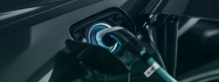 Close-up of an electric vehicle charging port with a charging cable plugged in.
