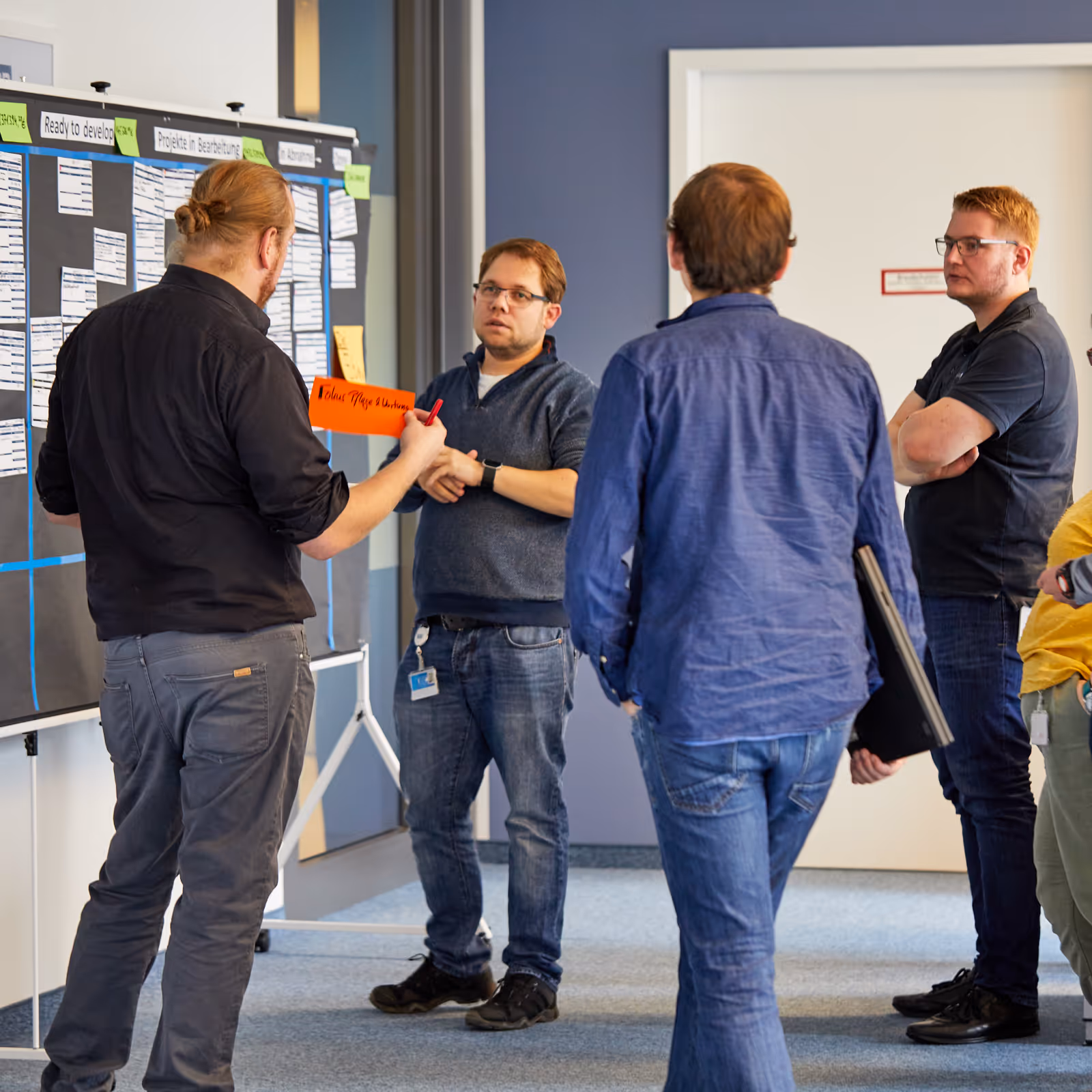 Vier Mitarbeiter kreieren eine Mindmap an einer Tafel