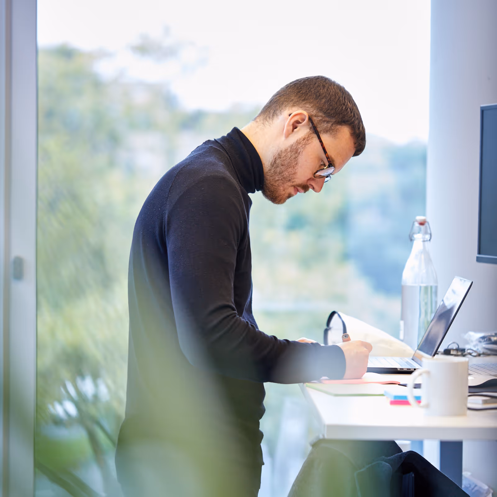 Büro Mitarbeiter schreibend am Stehschreibtisch