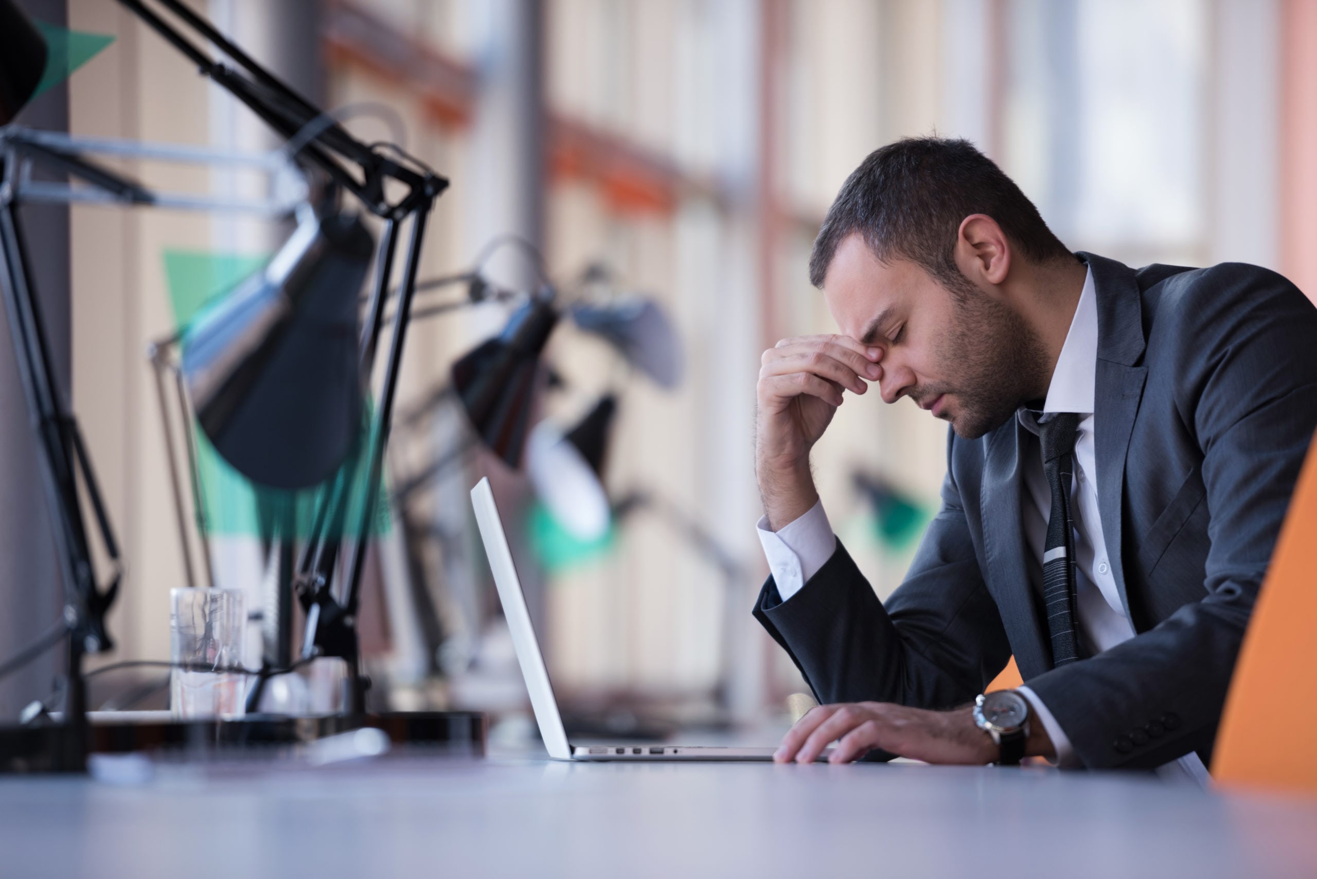 man at desk with head in his hands 