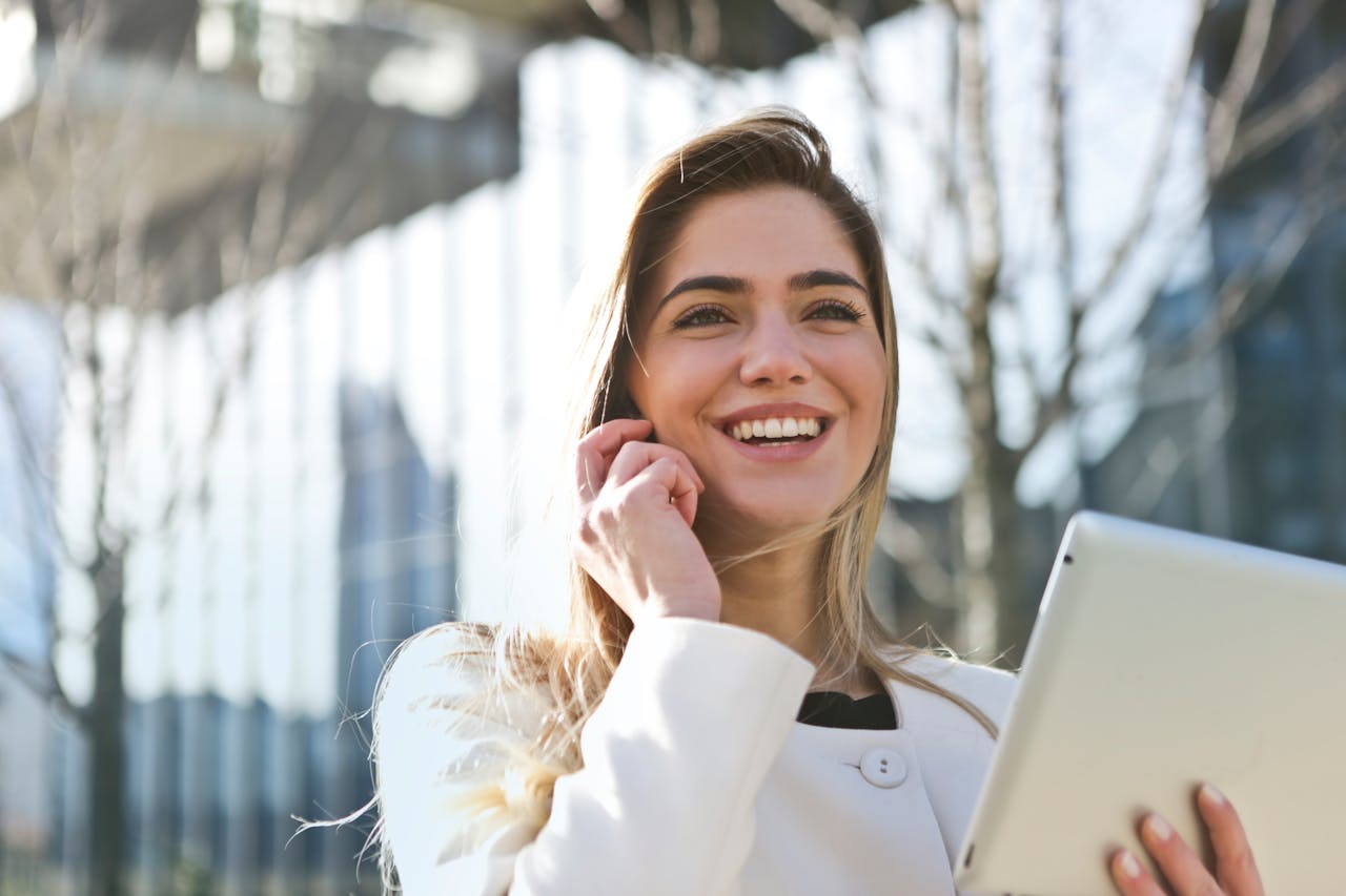 blonde woman in white talking and smiling on a cell phone