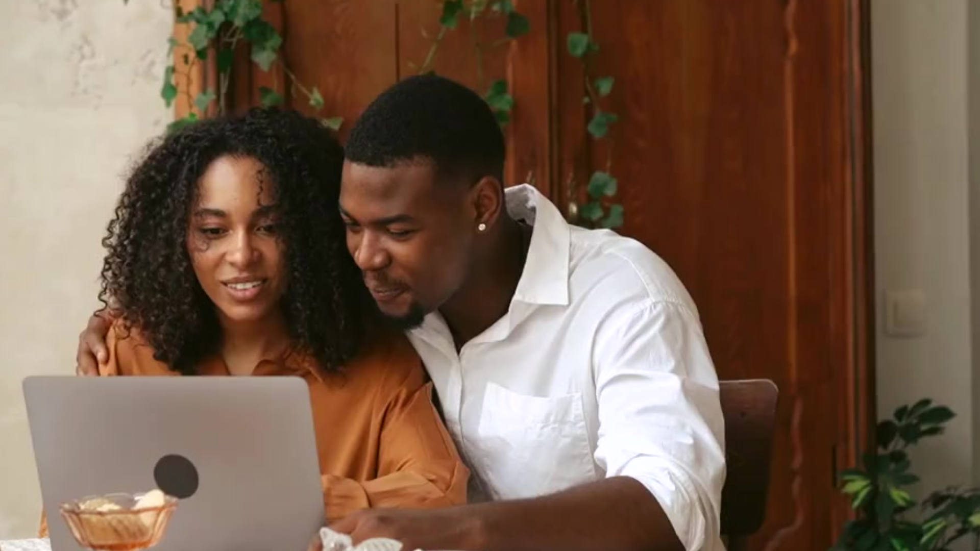 black man and woman sitting at laptop laughing