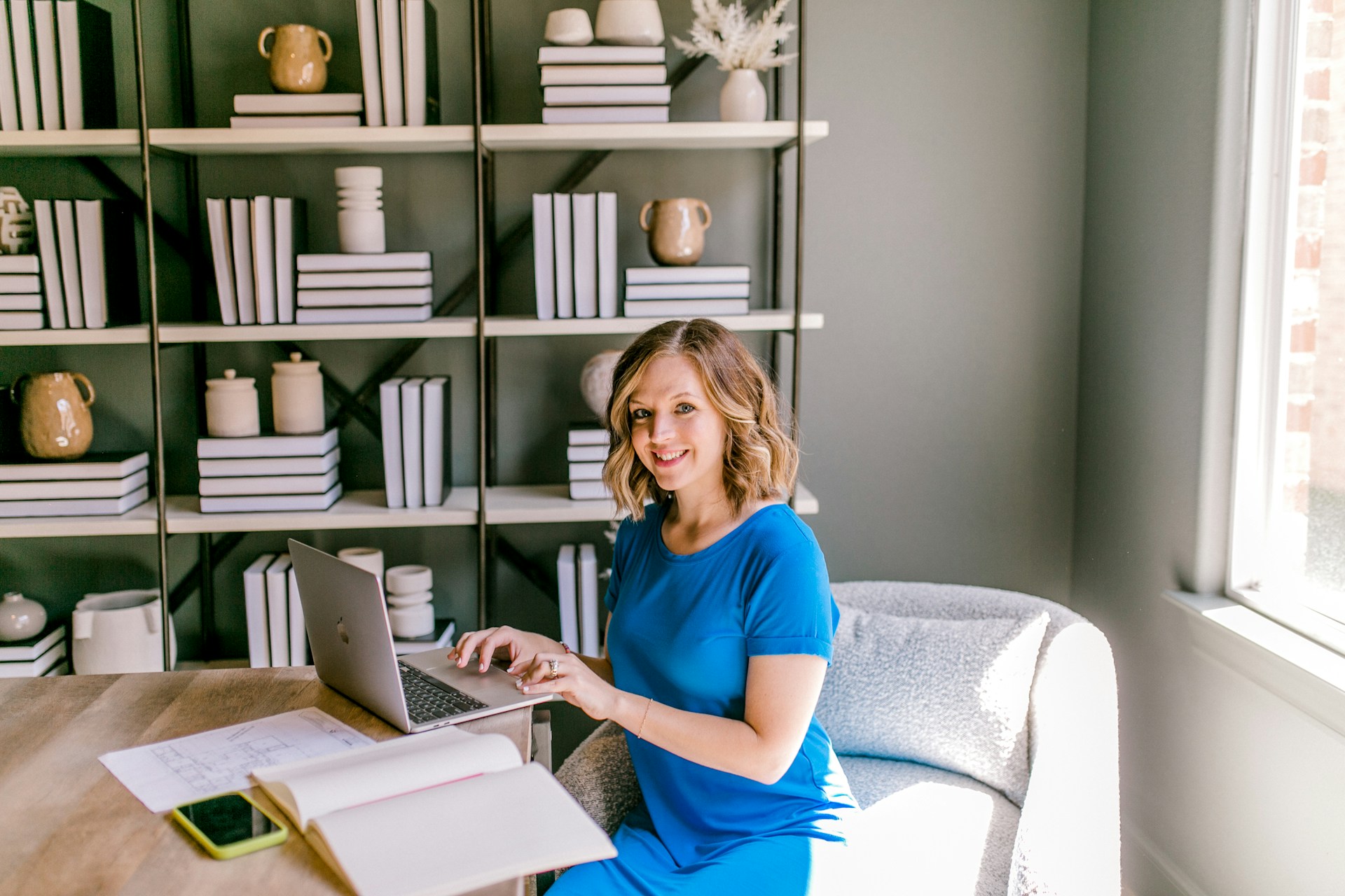 woman in blue dress working at laptop