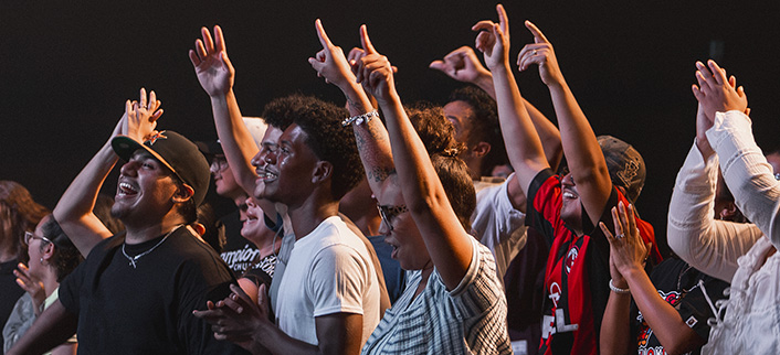 Group of people joyfully raising their hands and cheering at a lively event or concert.