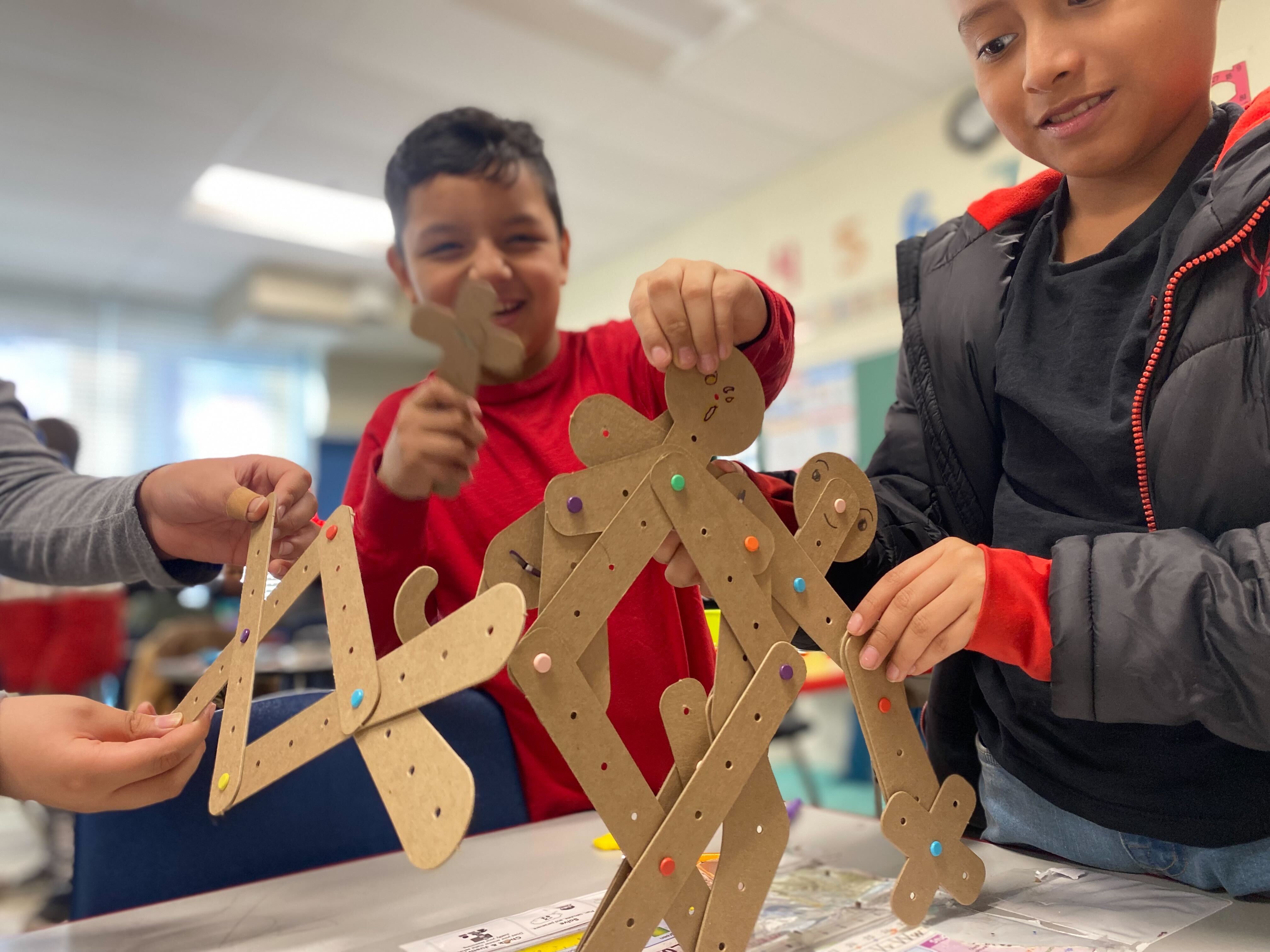 Learners building a tall cardboard structure together in a classroom