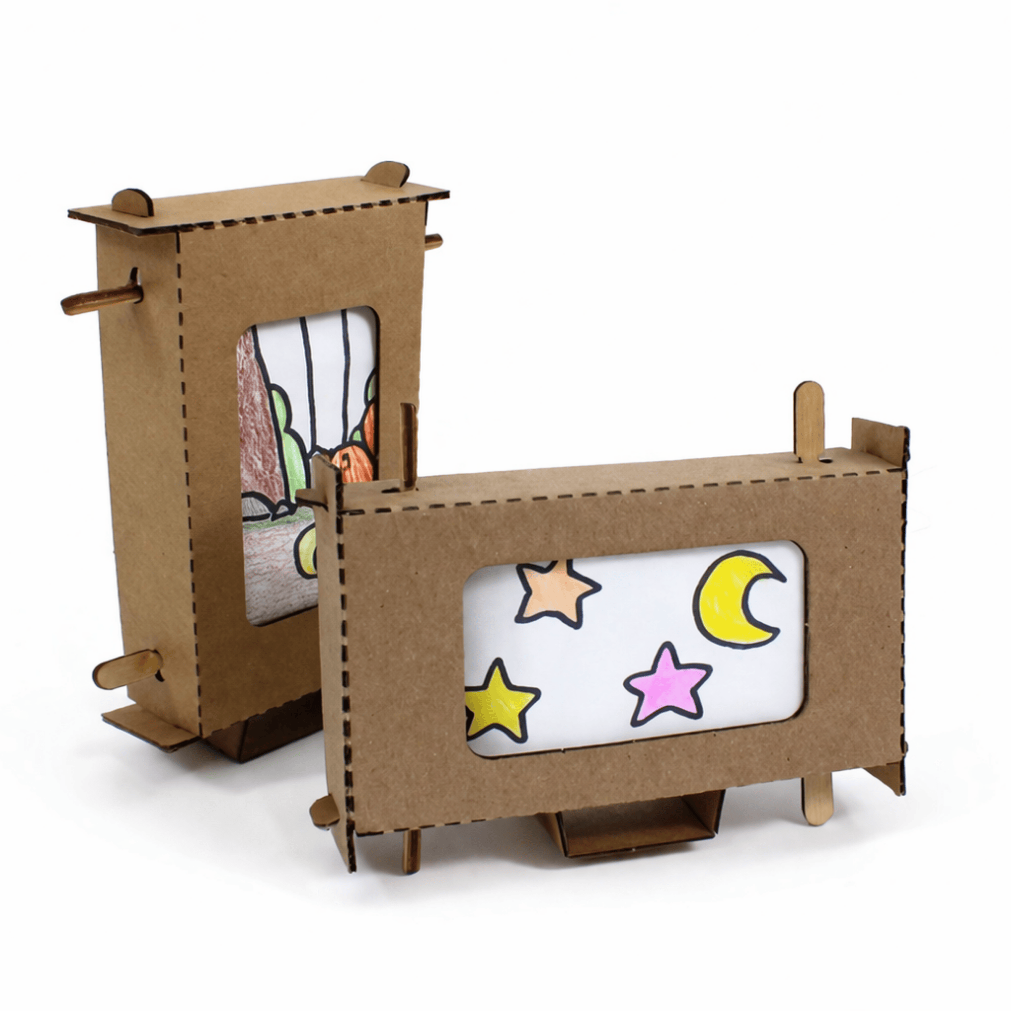 Two assembled Screen Machines cardboard scroll viewers side by side, each with a wooden crank handle, one showing a hand-drawn desert canyon scene and the other a night sky scene.