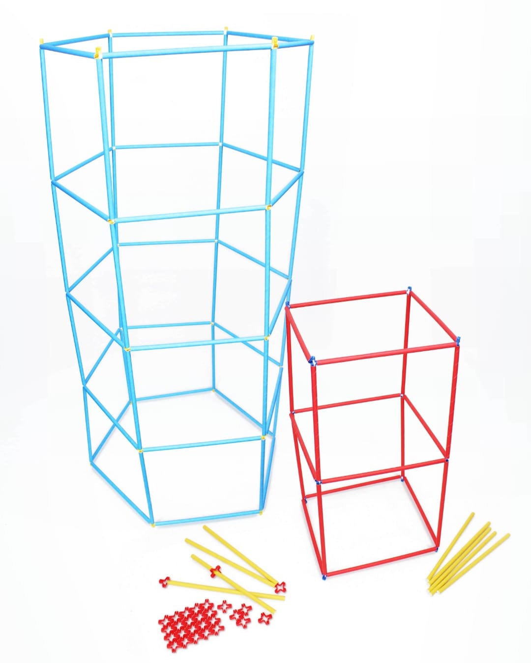 Two freestanding towers built from paper straws and plastic connectors: a taller light blue hexagonal tower with cross braces and a shorter red square tower, with loose straws and connectors in front.