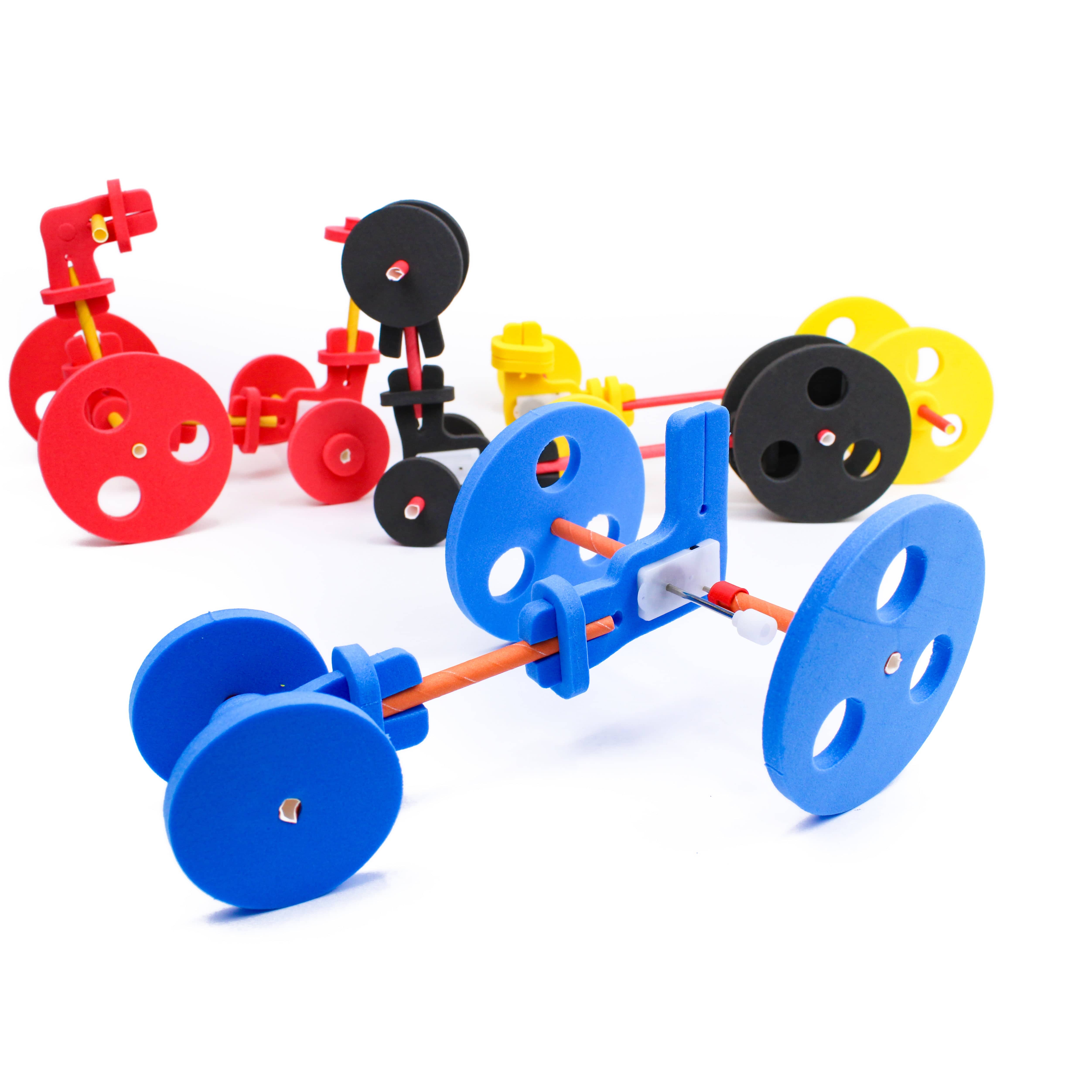 An assortment of assembled foam and straw wind-up vehicles in red, black, yellow, and blue, each with a different wheel size and axle layout.