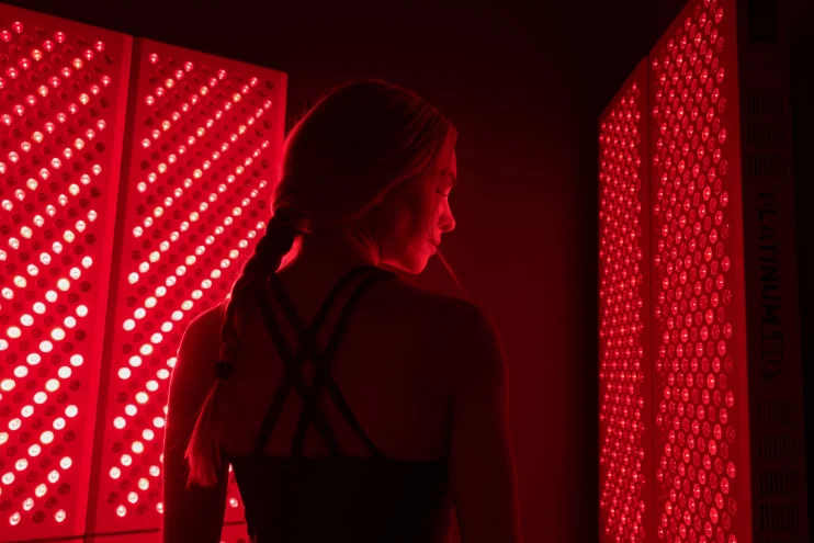 Woman standing between Red Light Therapy panels
