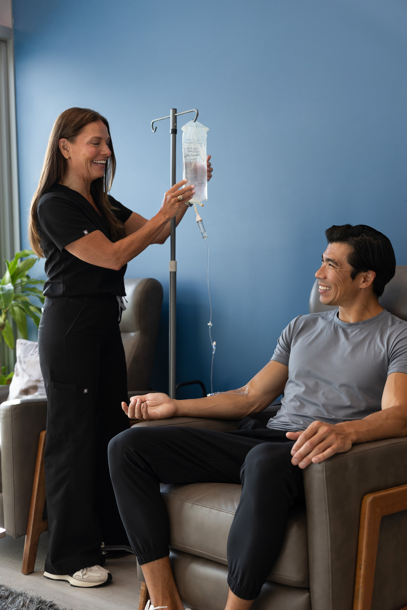 Restore Nurse adjusting an IV Drip for a smiling client