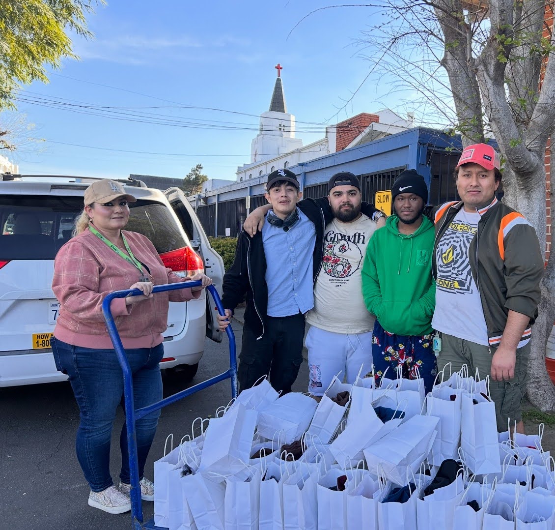 Penny Lane Centers volunteers in Los Angeles County standing together outdoors with a cart full of packed donation bags ready for community distribution.