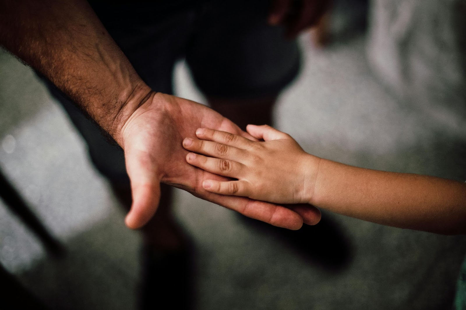 A child's hand rests on top of an adult's open palm.