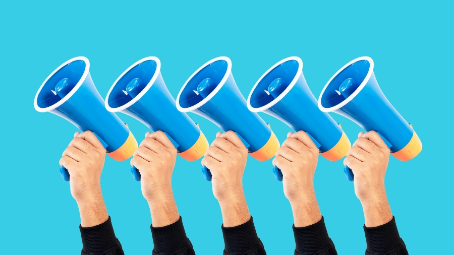 Four hands, each holding a blue and orange megaphone, are raised against a bright blue background. The image conveys the idea of communication, announcements, or amplification of messages.