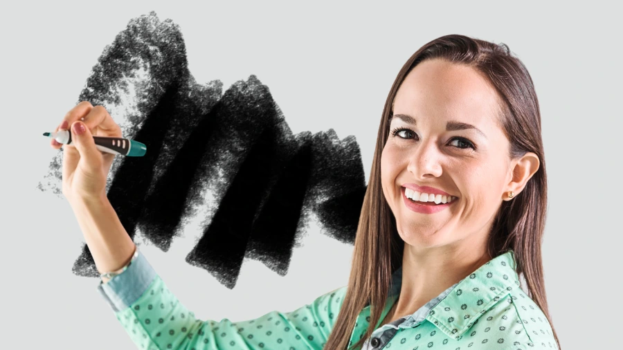 Smiling woman writing with a marker on a gray background, symbolizing creativity and building a memorable brand message.