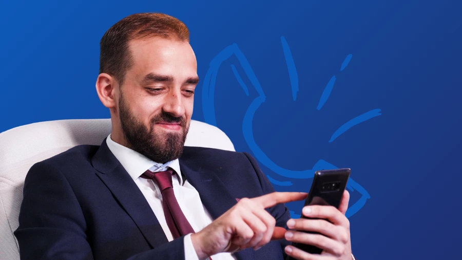 A confident professional in a suit smiling while checking his phone, representing identifying buying signals before a sales call.