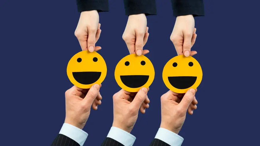 Hands exchanging smiley-face icons against a dark blue background, symbolizing customer satisfaction, positive experiences, and client feedback.