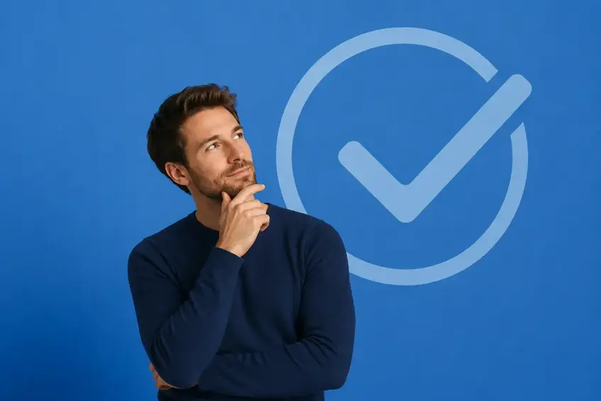 Thoughtful man standing in front of a large checkmark, symbolizing customer confidence, trust, and certainty before making a purchase.