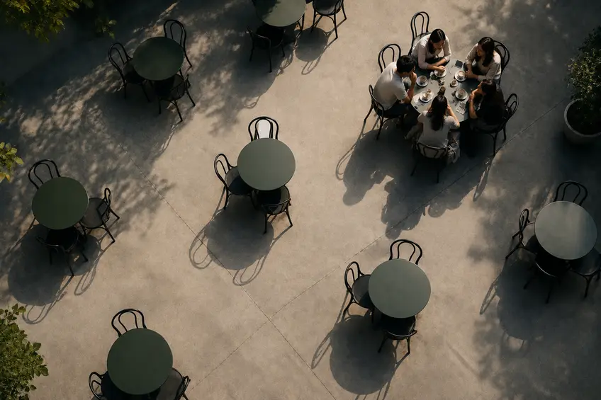 Overhead view of a café with one table full of people while surrounding tables remain empty, symbolizing creating demand and attracting customers before they compare alternatives.